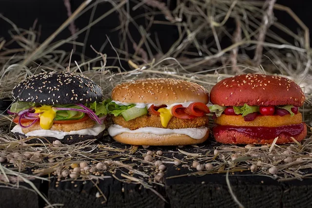 Три бургера с разноцветными булочками на фоне соломы — ИЗДИДЖИТЛ