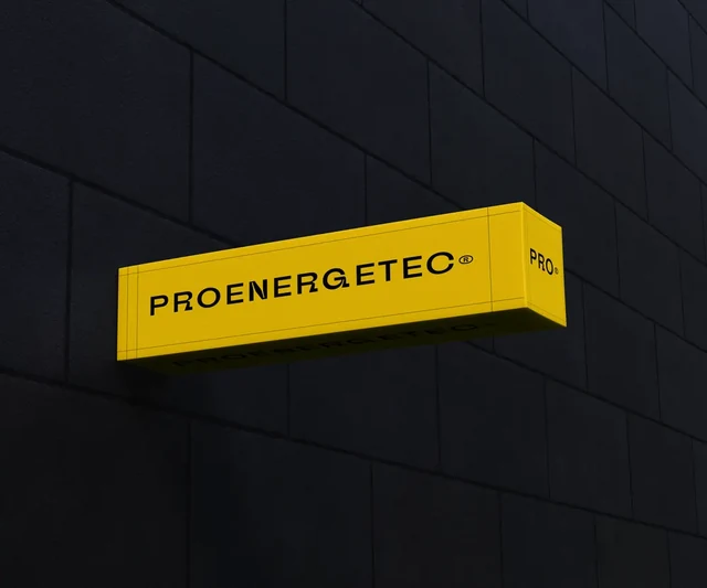 Прямоугольная жёлтая вывеска Proenergetec на тёмном фасаде — ИЗДИДЖИТЛ